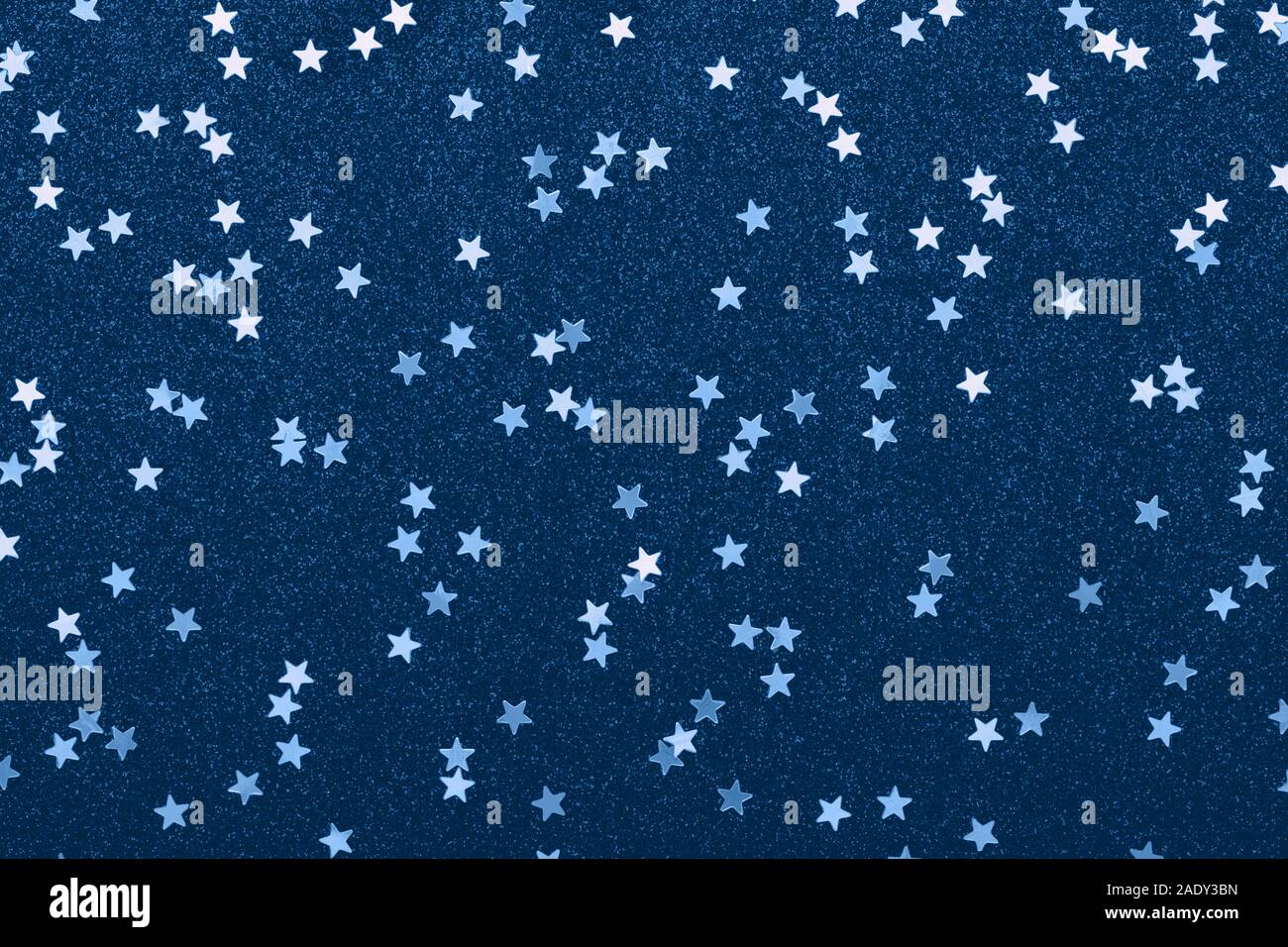 Classic stars confetti on blue color. Festive holiday background. Glitter sparkles. New Year 2020. Flat lay. Stock Photo