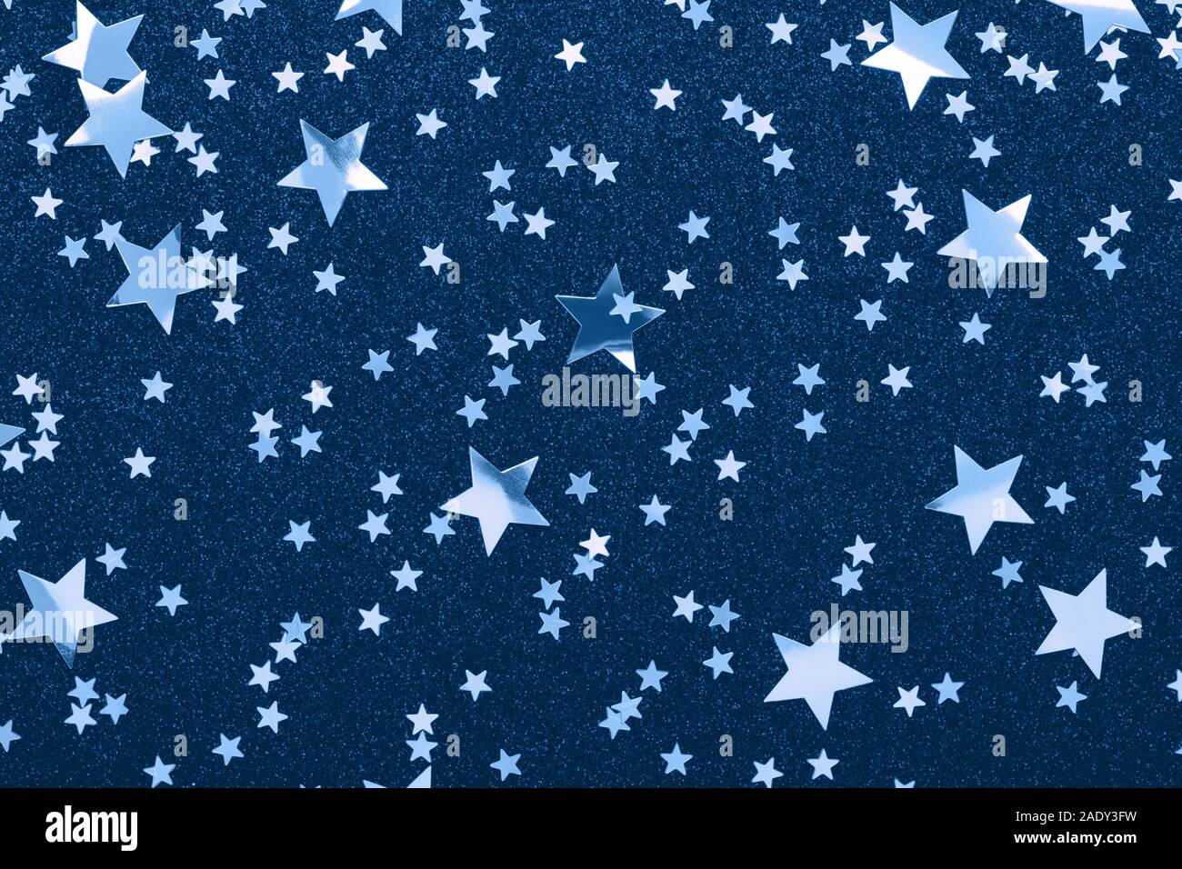 Classic stars confetti on blue color. Festive holiday background. Glitter sparkles. New Year 2020, flat lay. Stock Photo
