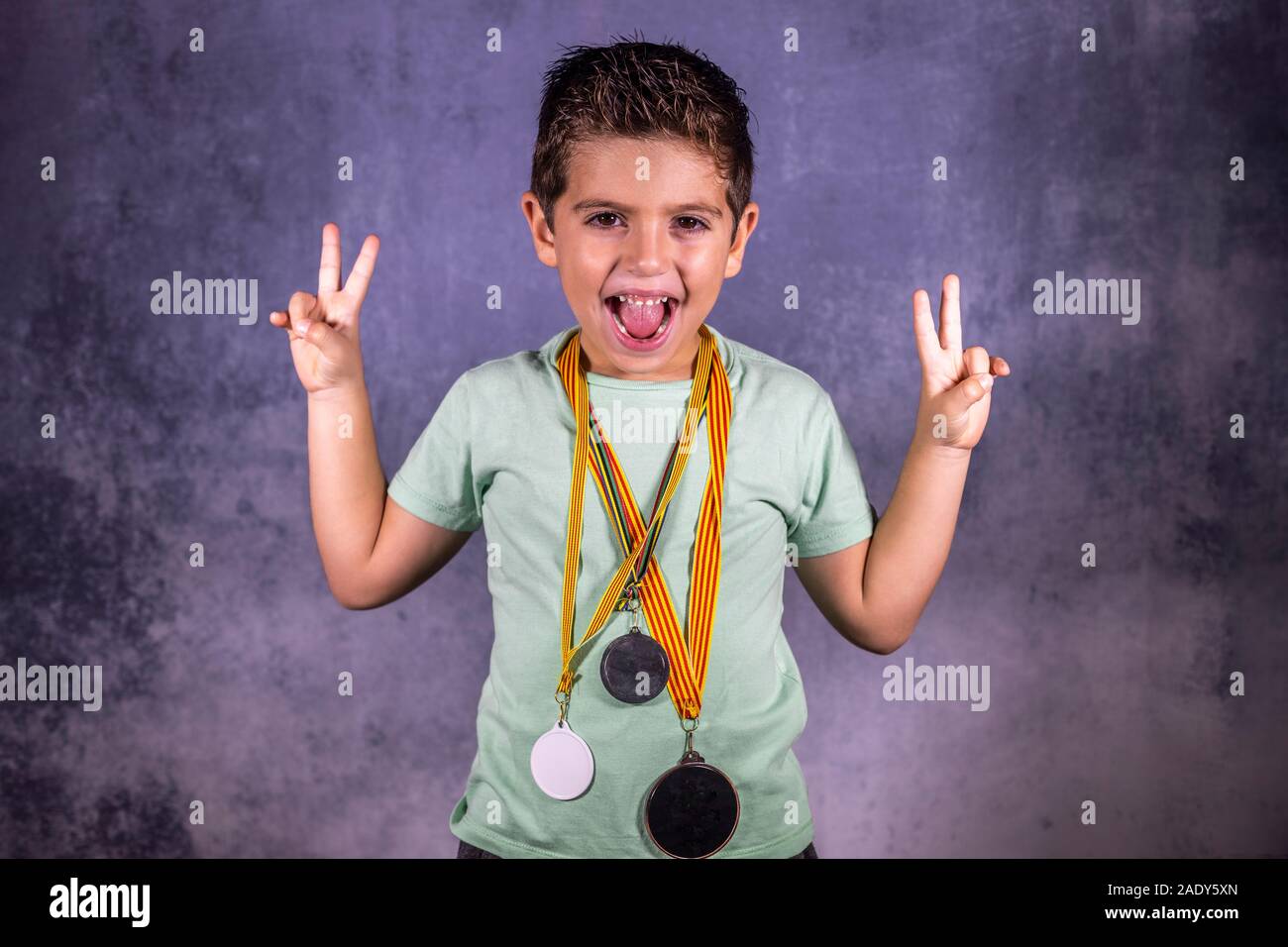 Euphoric kid with trhee medals isolated in blue Stock Photo