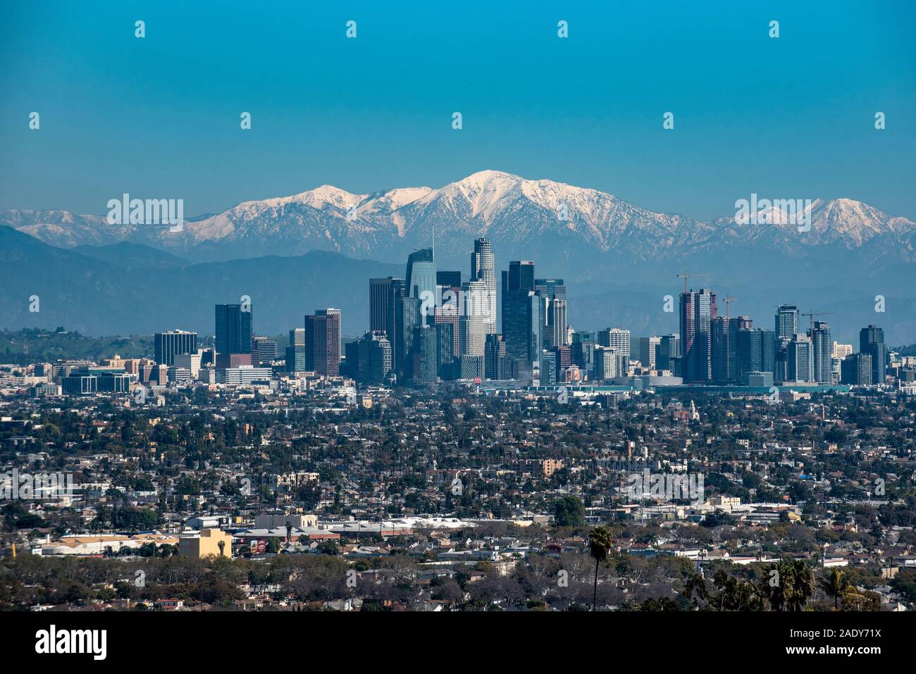 Mountain snow blankets peaks behind the skyscrapers of downtown Los Angeles, California Stock 