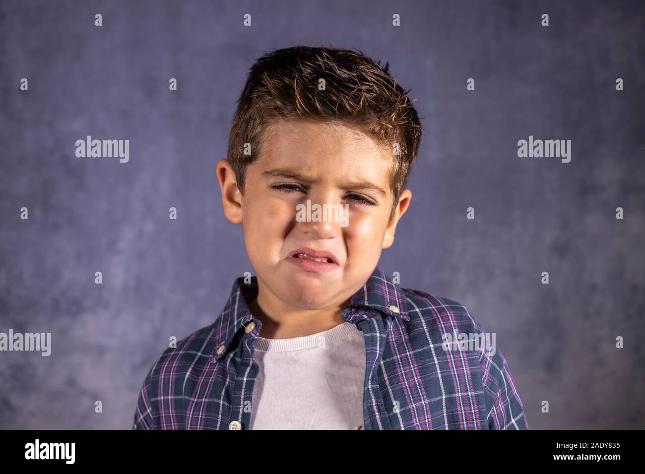 Little boy sad crying isolated in blue Stock Photo