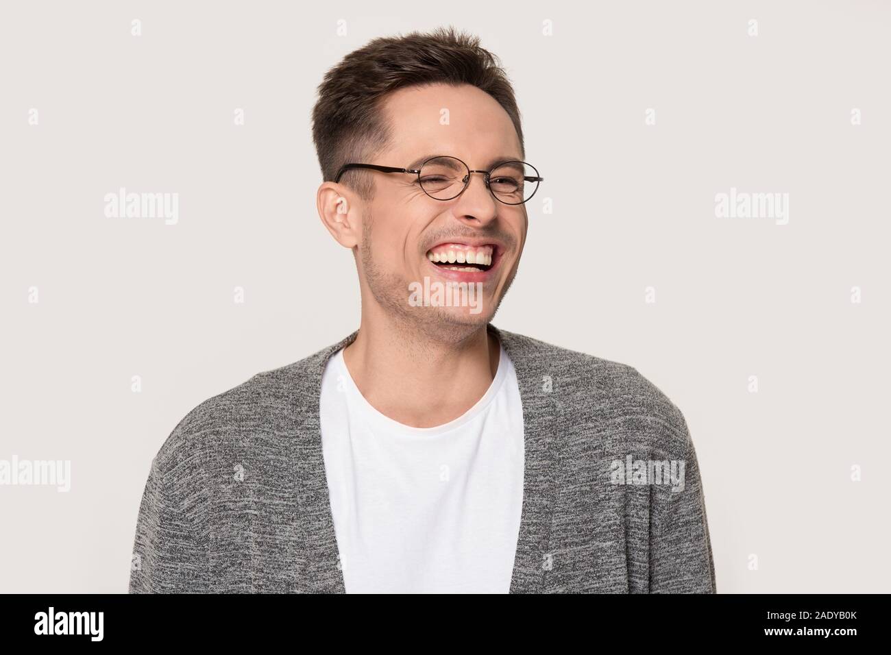 Happy young man laughing at funny joke squinting his eyes Stock Photo