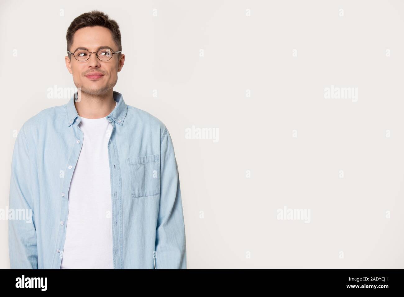 Young millennial man with cunning look isolated on grey background Stock Photo