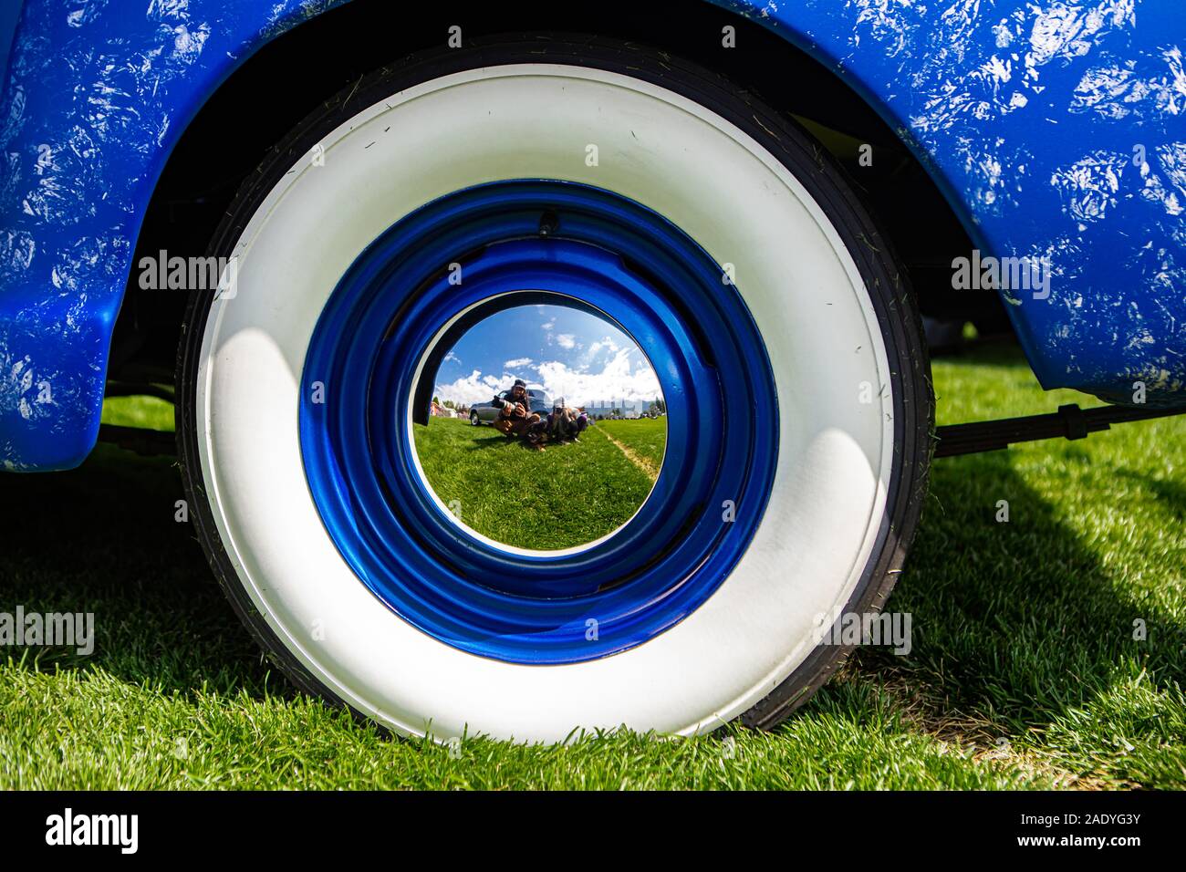 vintage classic American bright blue car wheels on the grass, Close up on the Steel Wheel Chrome center With reflection, and Whitewall tire Stock Photo