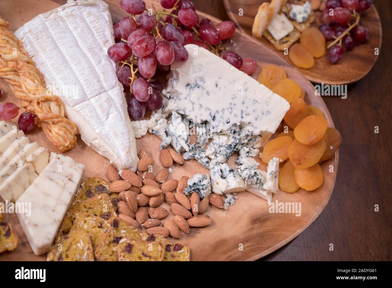 Wooden cheese platter with brie, assorted cheeses, red grapes, crackers