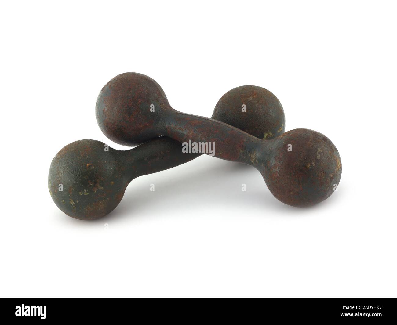 Two old heavy covered with a touch of rust dumbbells lie on each other isolated on white background. Vintage sports equipment closeup Stock Photo