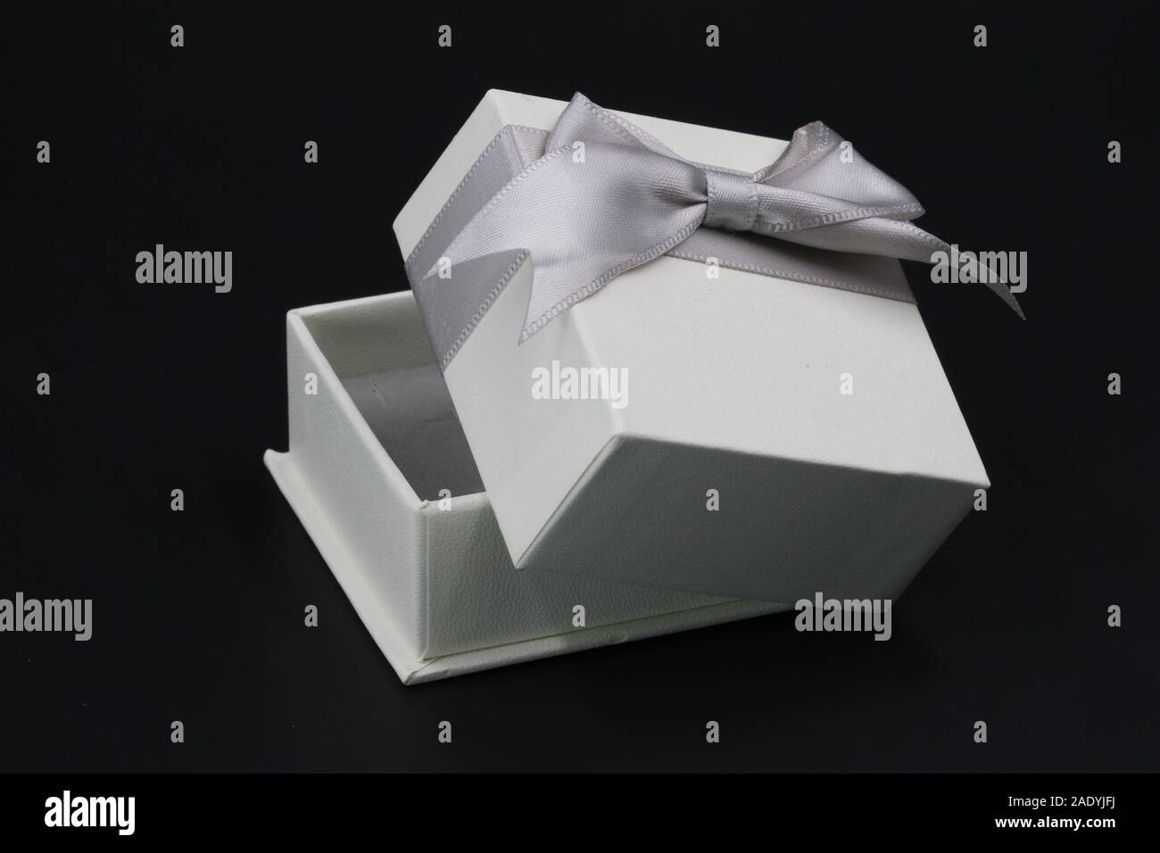 white ring gift box with silver bow isolated on a black background. Stock Photo
