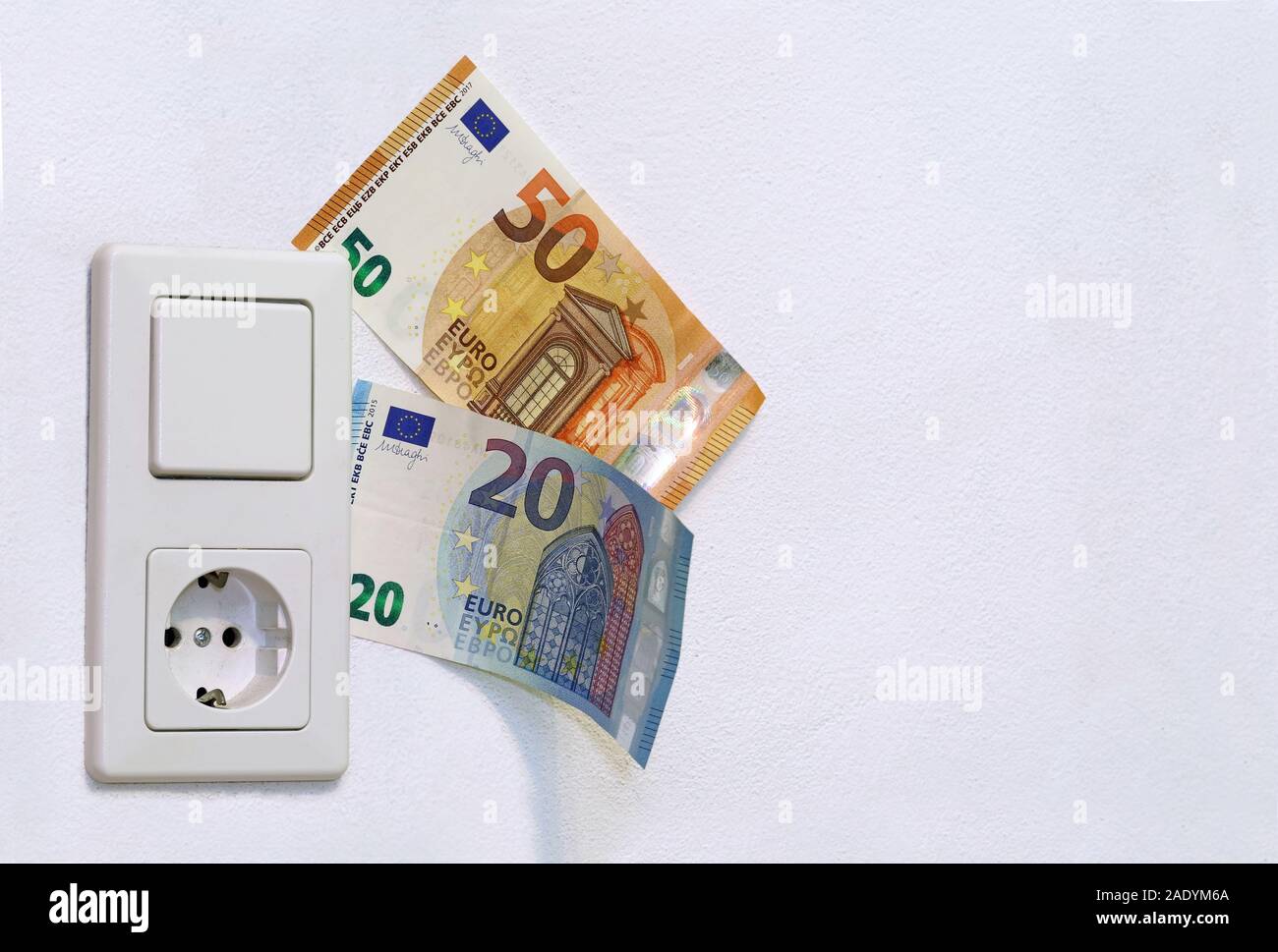 light switch with socket and euro banknotes on white wall, copy space Stock Photo