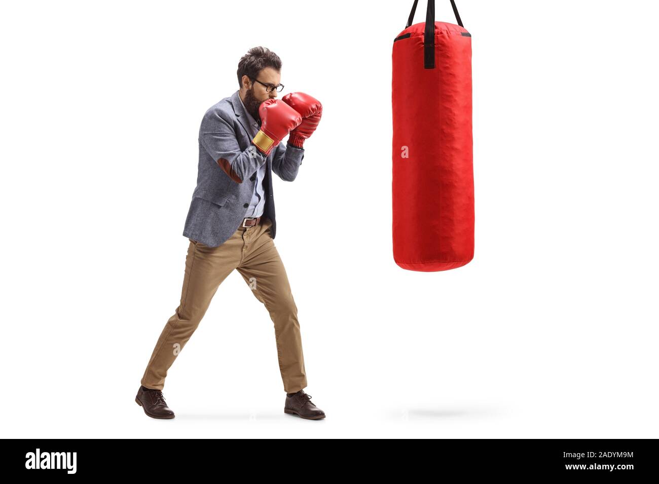 Full length profile shot of a man punching a bag with boxing gloves