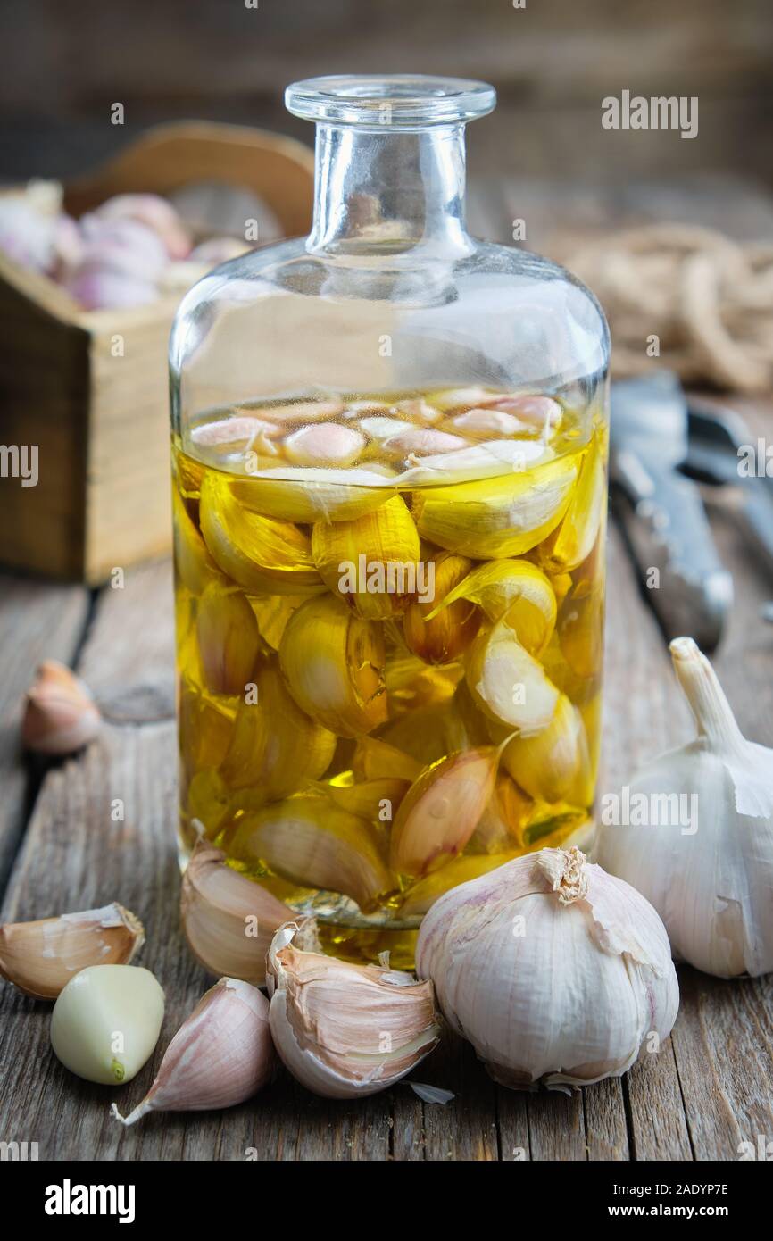 Garlic aromatic flavored oil or infusion bottle and garlic cloves. Stock Photo