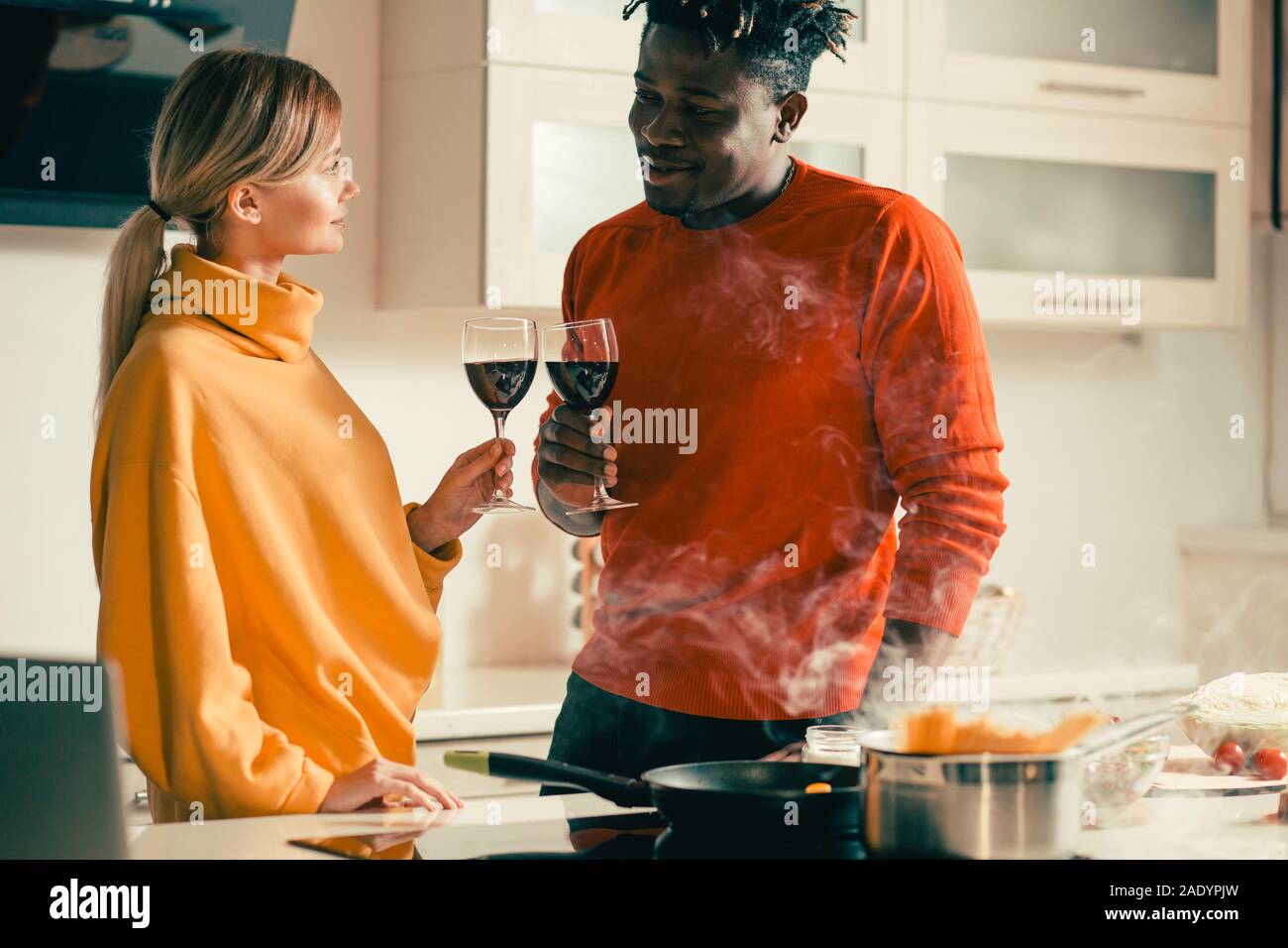 Young couple looking relaxed while drinking wine in the kitchen Stock Photo