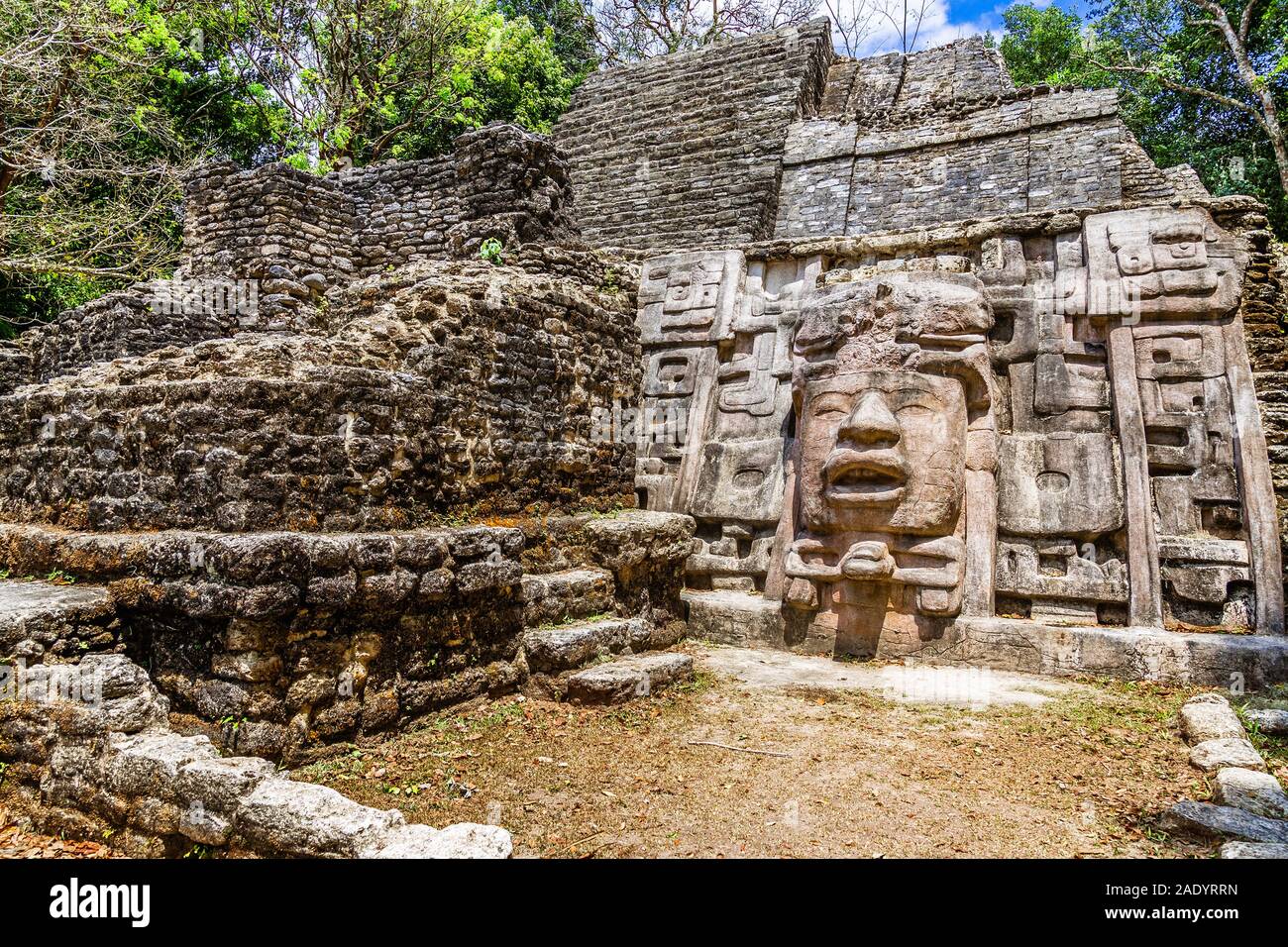 Old ancient stone Mayan pre-columbian civilization pyramid with carved face and ornament hidden in the forest, Lamanai archeological site, Orange Walk Stock Photo