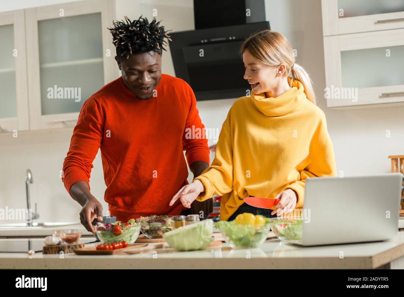 Positive couple smiling while cooking in the kitchen Stock Photo - Alamy
