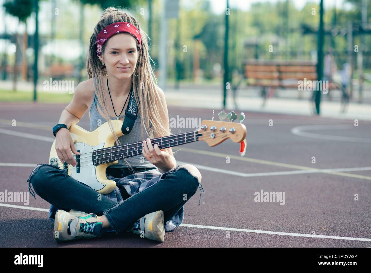Long haired lady smiling and looking at you while sitting with the guitar Stock Photo