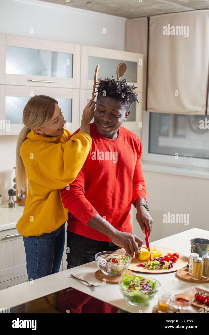Positive lady putting wooden spoons behind the head of young man Stock Photo Alamy
