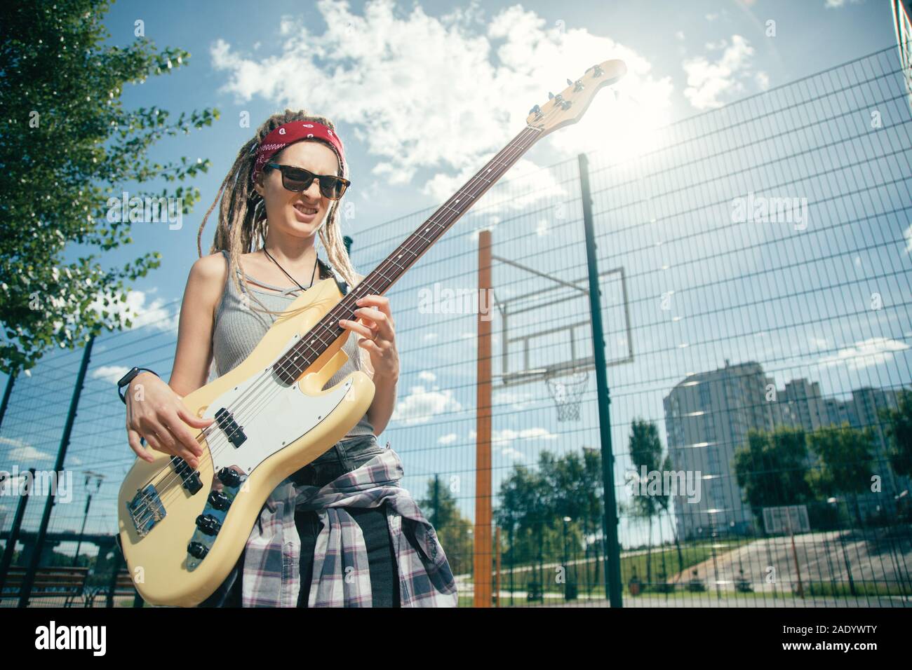 Expressive lady enjoying playing the guitar while being in the yard Stock Photo