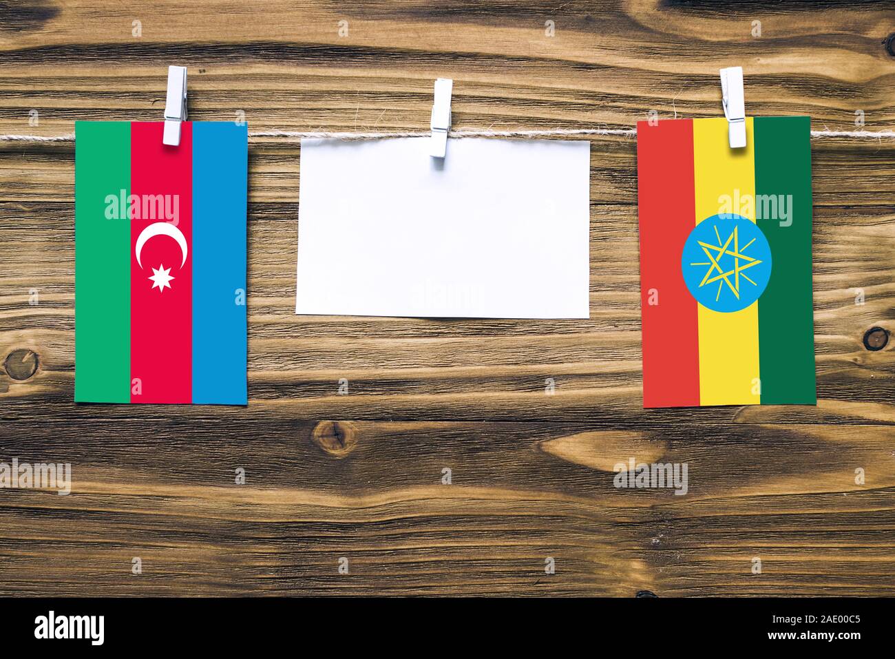 Hanging flags of Azerbaijan and Ethiopia attached to rope with clothes pins with copy space on white note paper on wooden background.Diplomatic relati Stock Photo