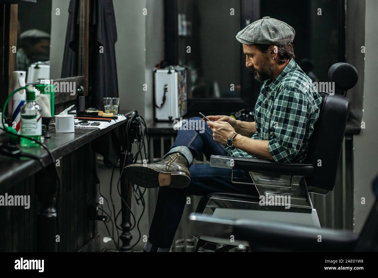 Calm Man Crossing Legs While Sitting With Smartphone In Barbershop Stock Photo Alamy alamy