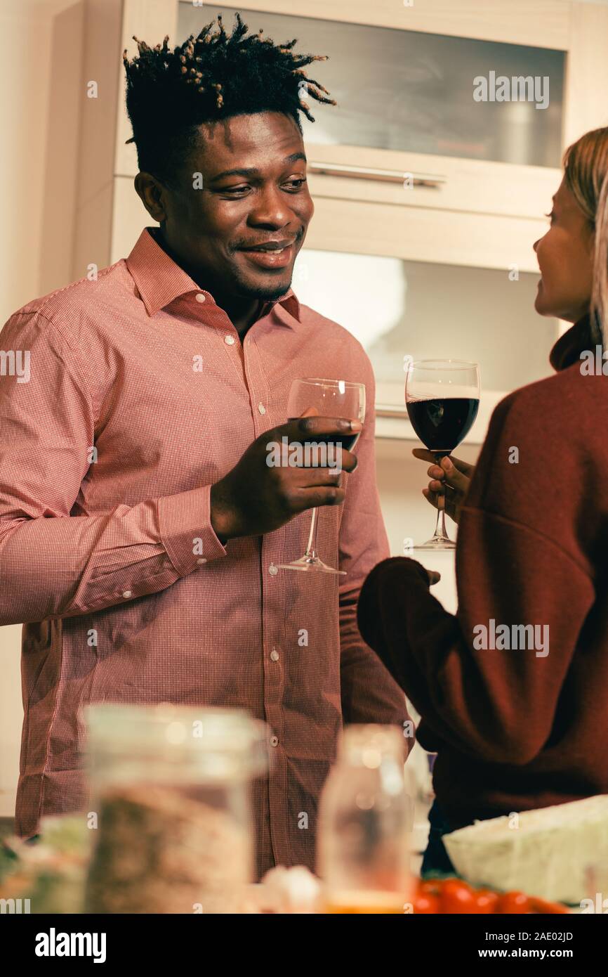 Smiling man looking at his girlfriend while drinking wine with her