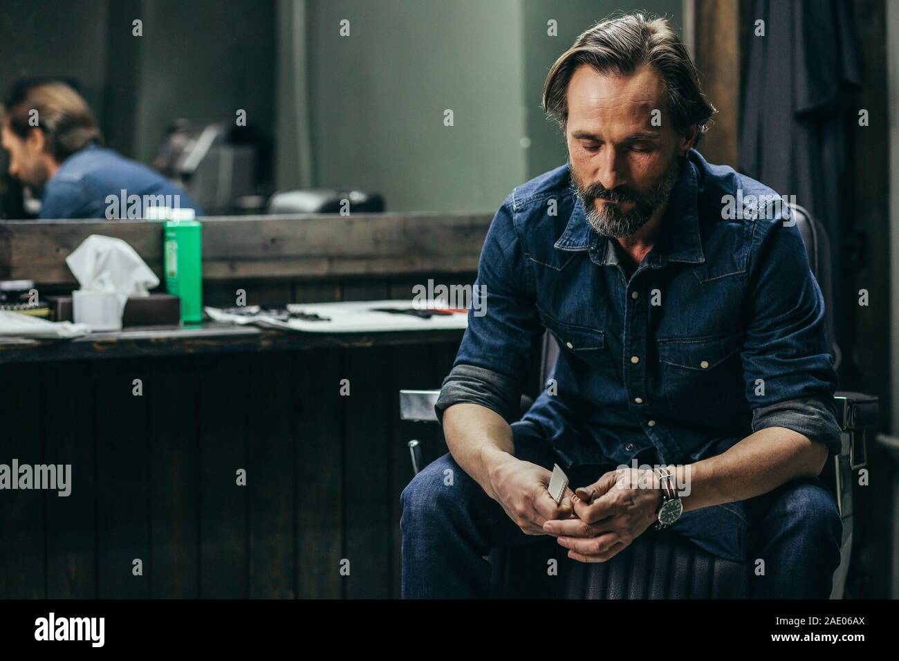 Bearded man looking tired while sitting with comb in hands Stock Photo