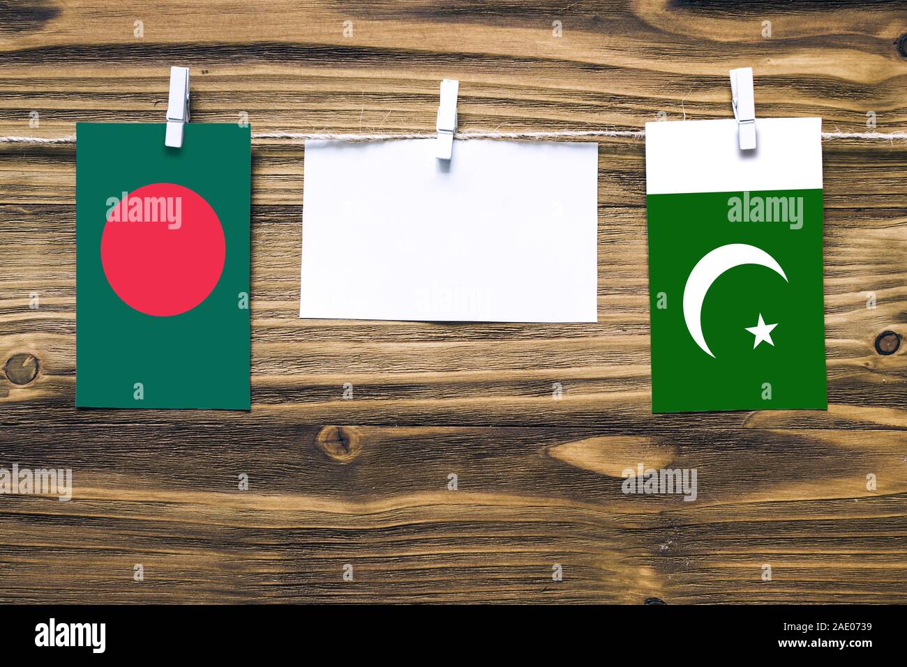 Hanging flags of Bangladesh and Pakistan attached to rope with clothes pins with copy space on white note paper on wooden background.Diplomatic relati Stock Photo