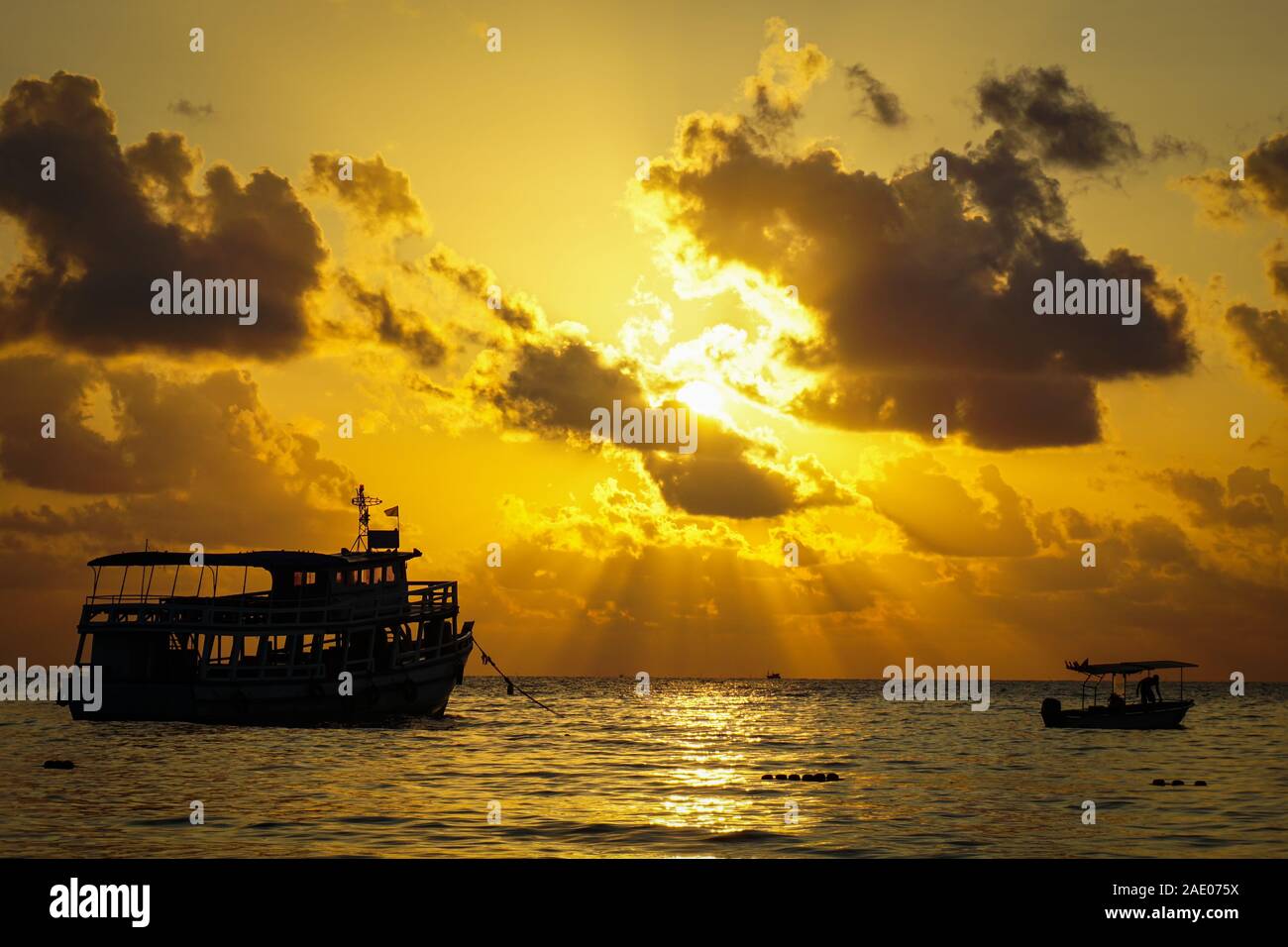 Fishing boat trawler and fisherman on the water ocean and dramatic clouds sky at sunrise / fishing boat sea at dawn silhouette sunset Stock Photo