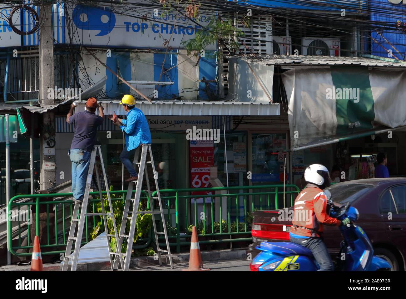 Bangkok, Thailand - December 4, 2019 : Two workers on ladders, they are installing new aluminum roof for the shop Stock Photo