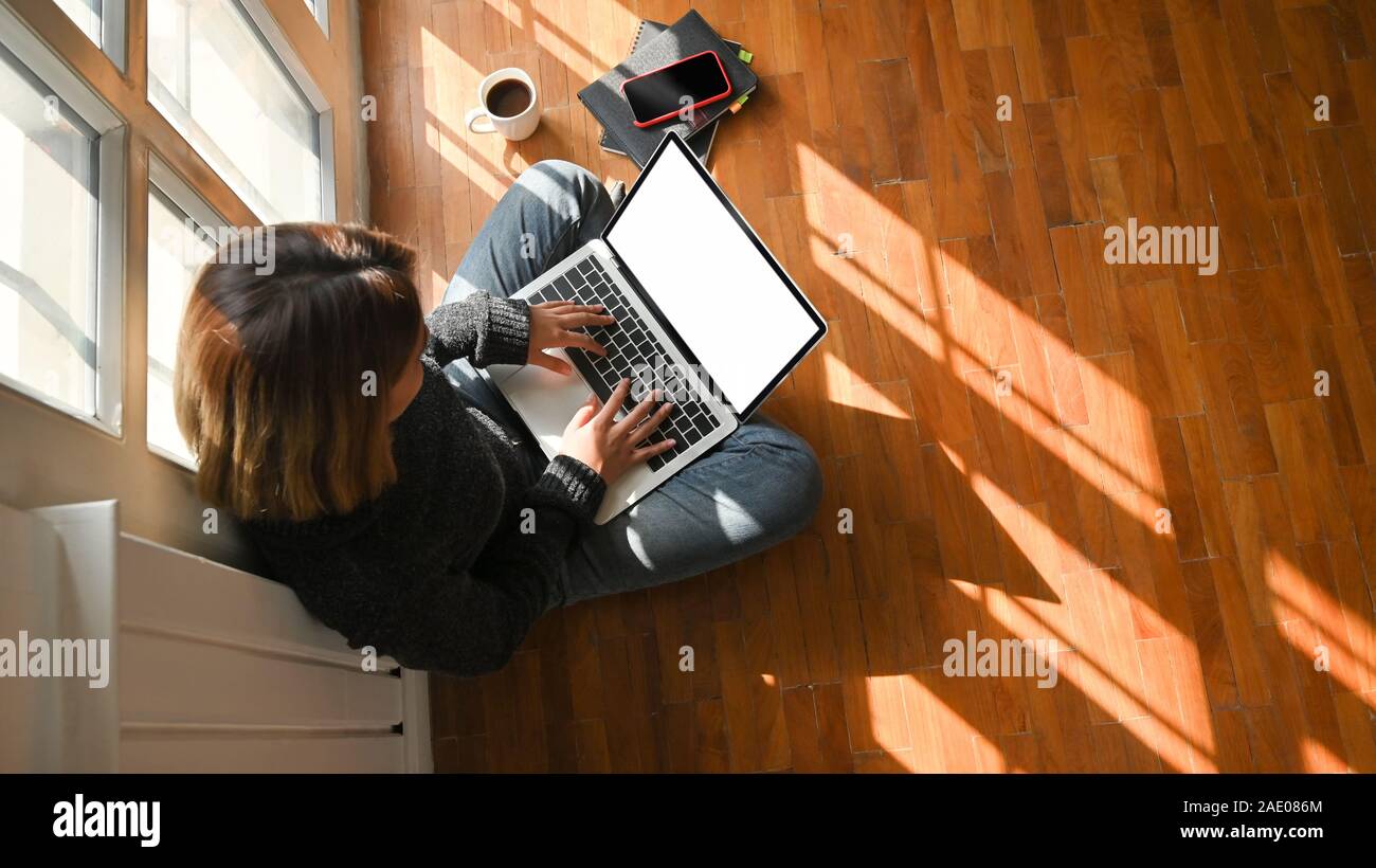 Female sitting on floor and using mockup laptop computer Stock Photo ...