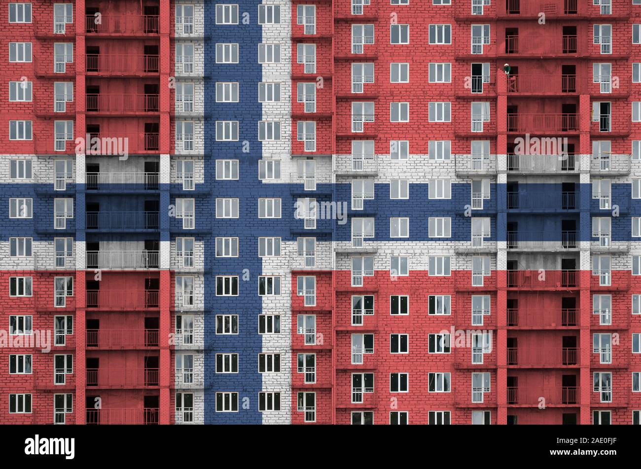 Norway flag depicted in paint colors on multi-storey residental building under construction. Textured banner on big brick wall background Stock Photo