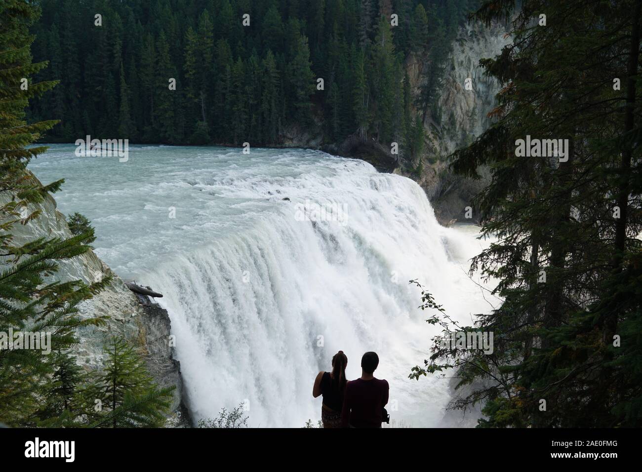 A couple enjoying the view of a large waterfall in Yoho National Park in Canada Stock Photo
