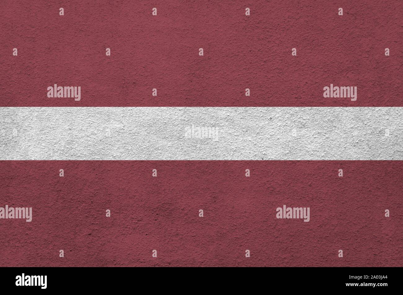 Latvia flag depicted in bright paint colors on old relief plastering wall close up. Textured banner on rough background Stock Photo