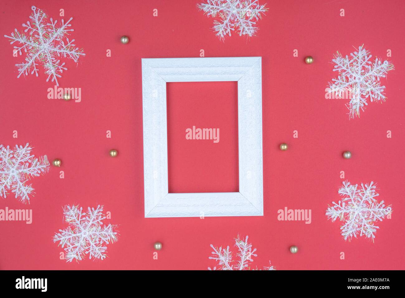 Christmas holidays composition, top view of snowflake decorations and picture frame on red background with copy space for text. Flat lay, winter, post Stock Photo