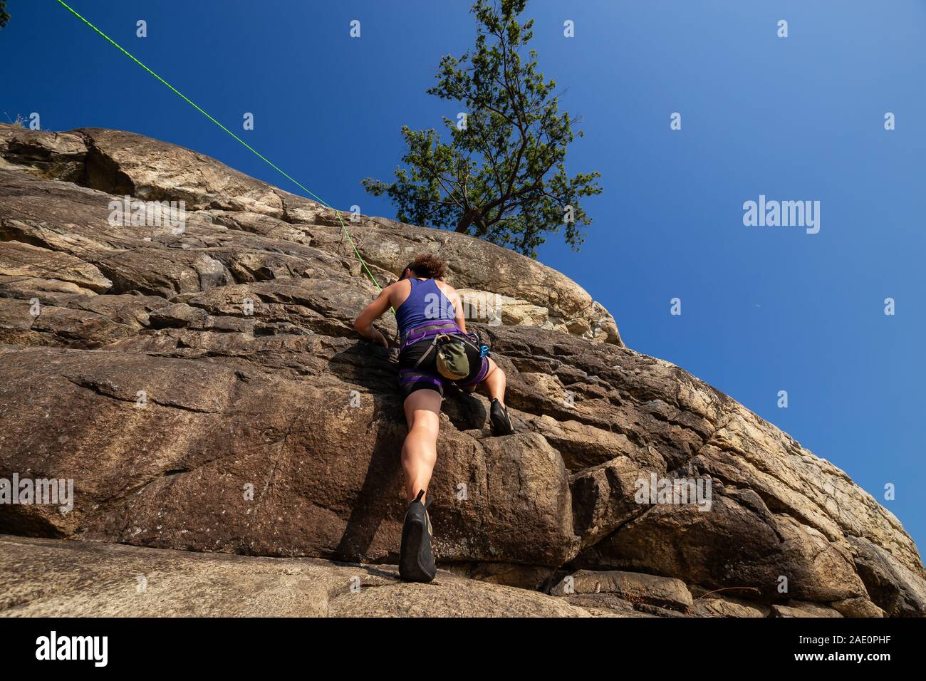 Adventurous Girl is Rock Climbing up a Steep Cliff during a summer sunset. Taken in Lighthouse