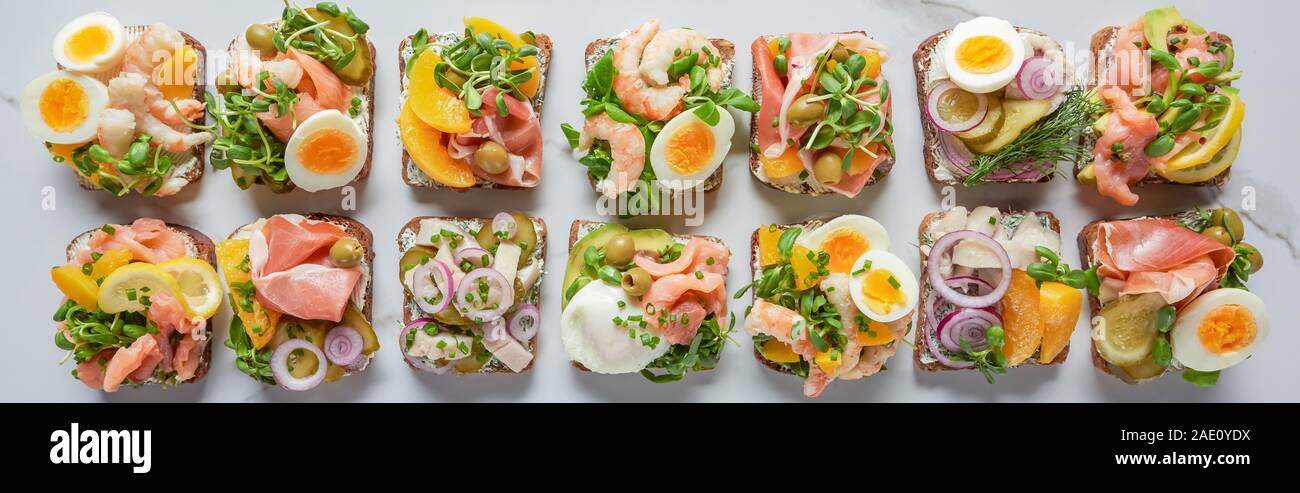 panoramic shot of delicious danish smorrebrod sandwiches on white marble surface Stock Photo