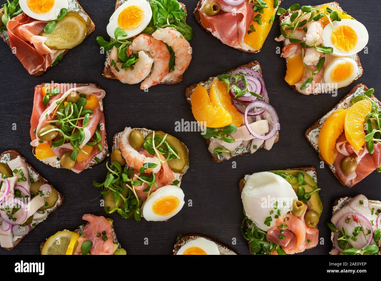 top view of rye bread with cooked smorrebrod sandwiches on grey surface ...