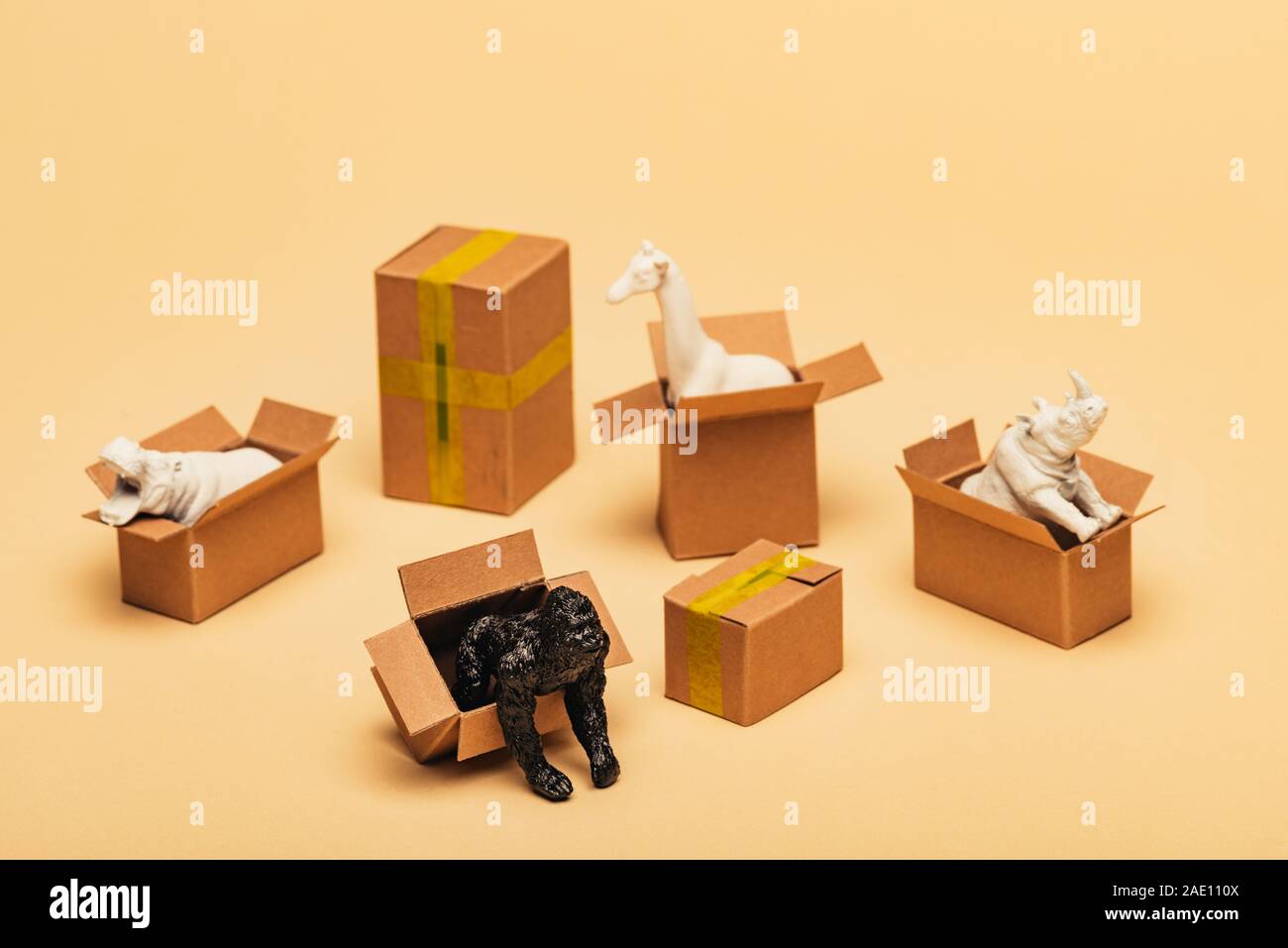 Selective focus of animal toys in cardboard boxes on yellow background, animal welfare concept Stock Photo