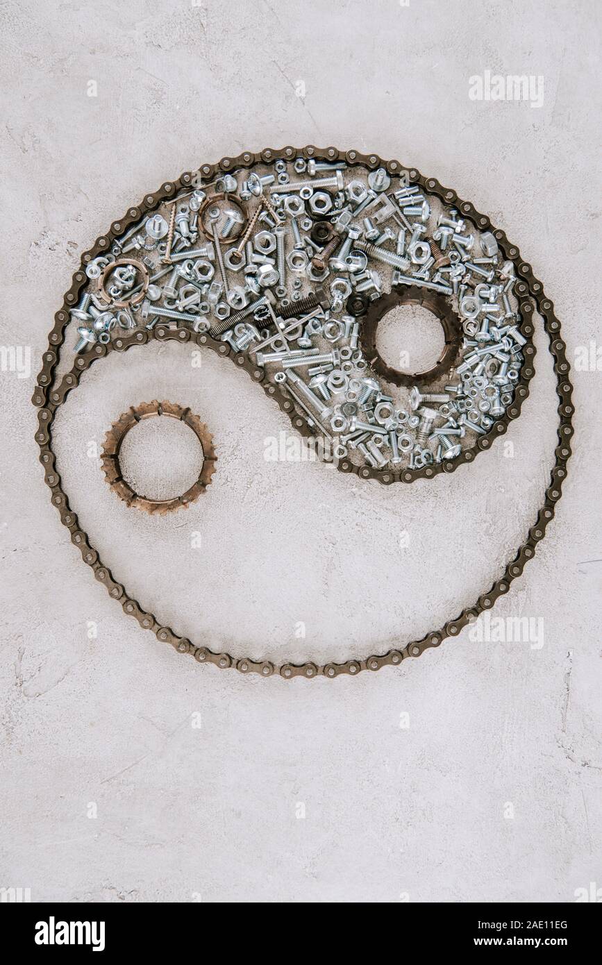 top view of aged metal gears and screws arranged in taijitu symbol on grey background Stock Photo