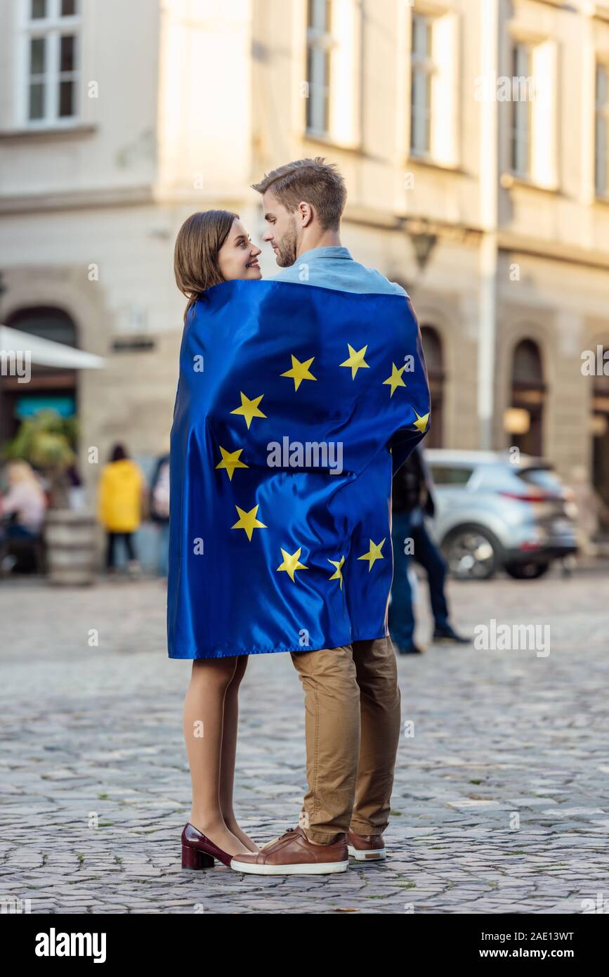 happy tourists, wrapped in flag of european union, looking at each other on street Stock Photo