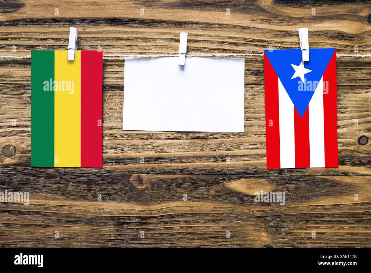 Hanging flags of Bolivia and Puerto Rico attached to rope with clothes pins with copy space on white note paper on wooden background.Diplomatic relati Stock Photo
