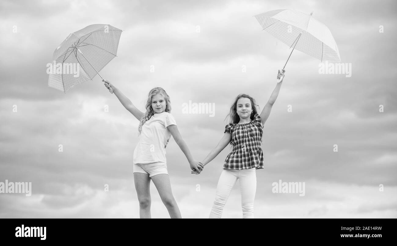 Follow me. school time. autumn season. rainy weather forecast. fall kid fashion. Feeling protected at this autumn day. happy small girls with umbrella. positive and bright mood. best friends. Stock Photo