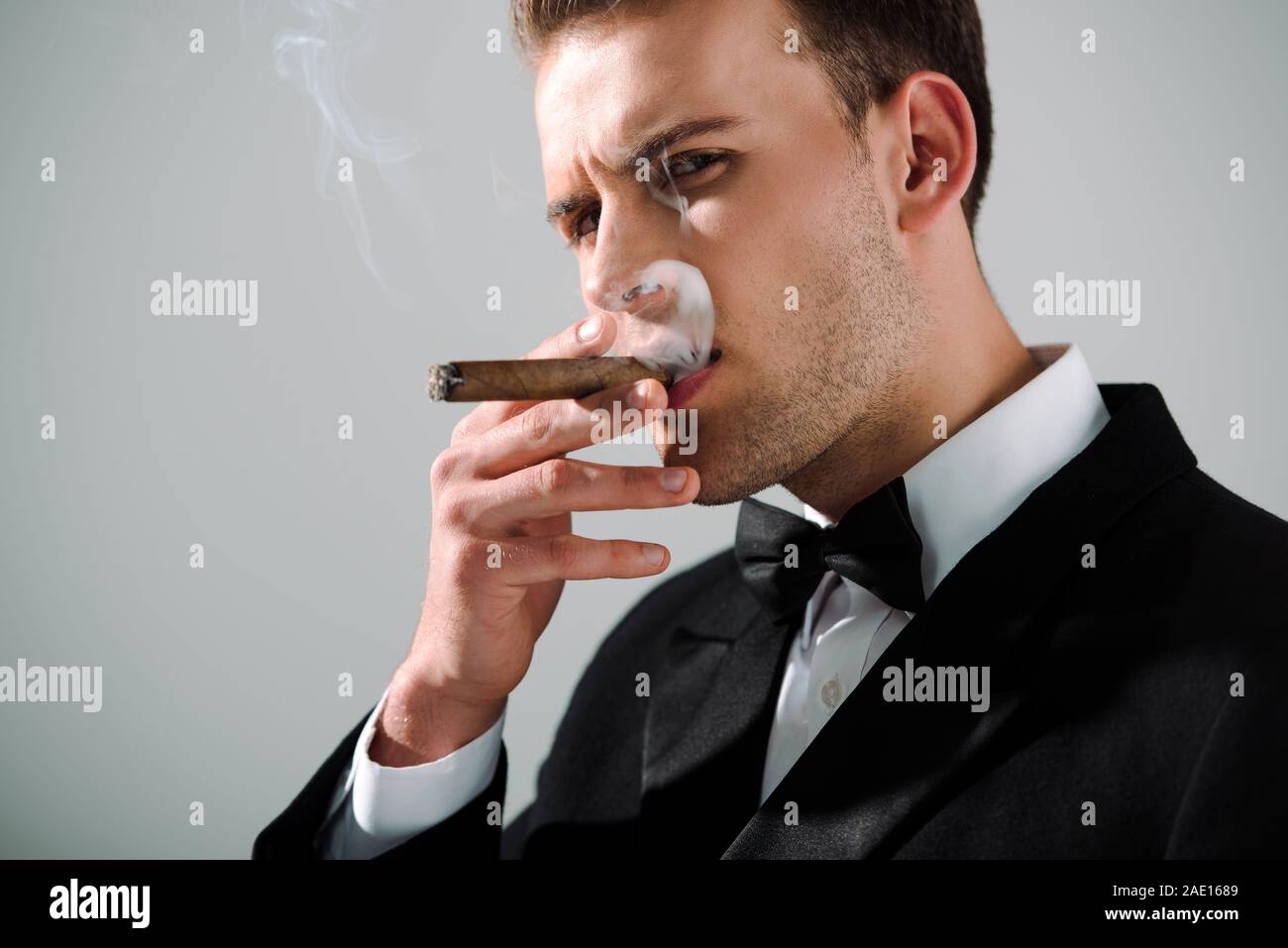 handsome and rich man smoking cigar isolated on grey Stock Photo