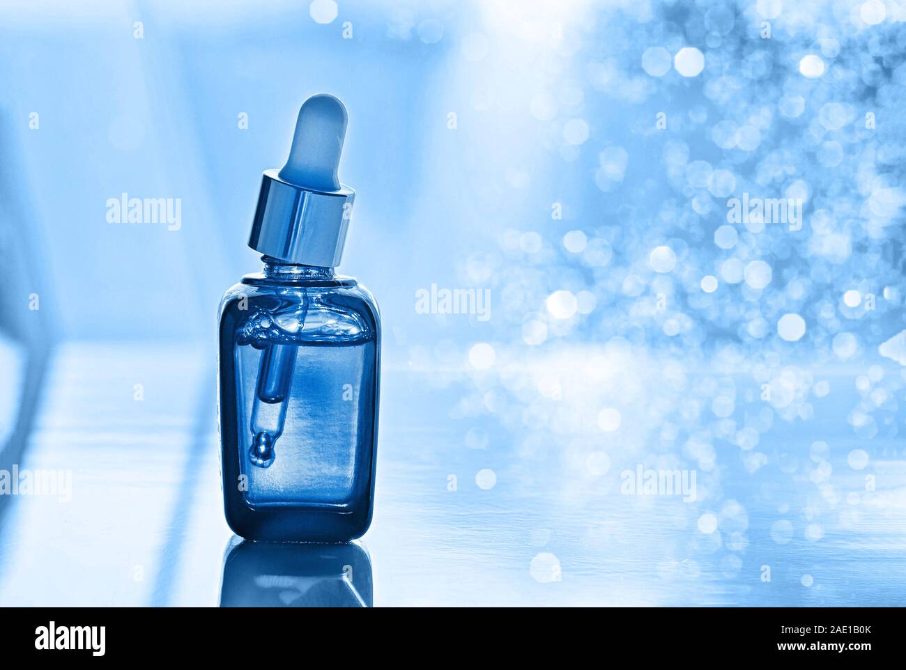 Bottle with fluid collagen of hyaluronic acid. Toned blue. Close up. Stock Photo