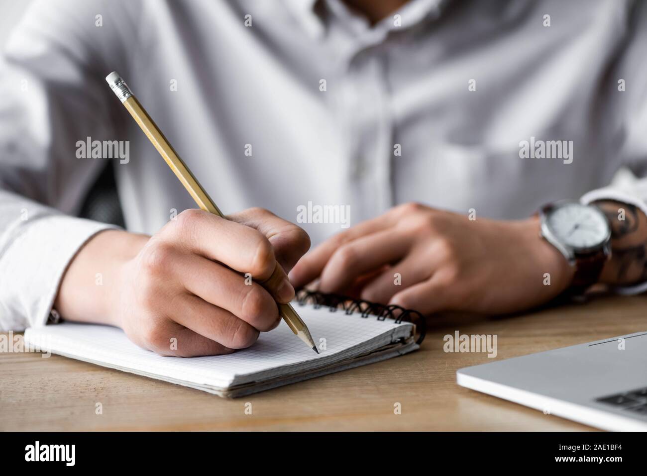 cropped view of seo manager writing in notebook during webinar in office Stock Photo