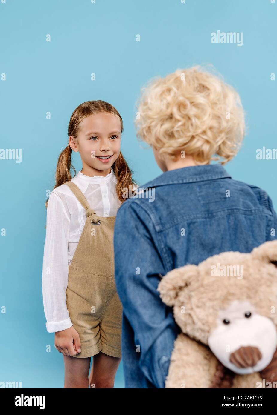 back view of boy holding teddy bear and smiling kid looking at him ...