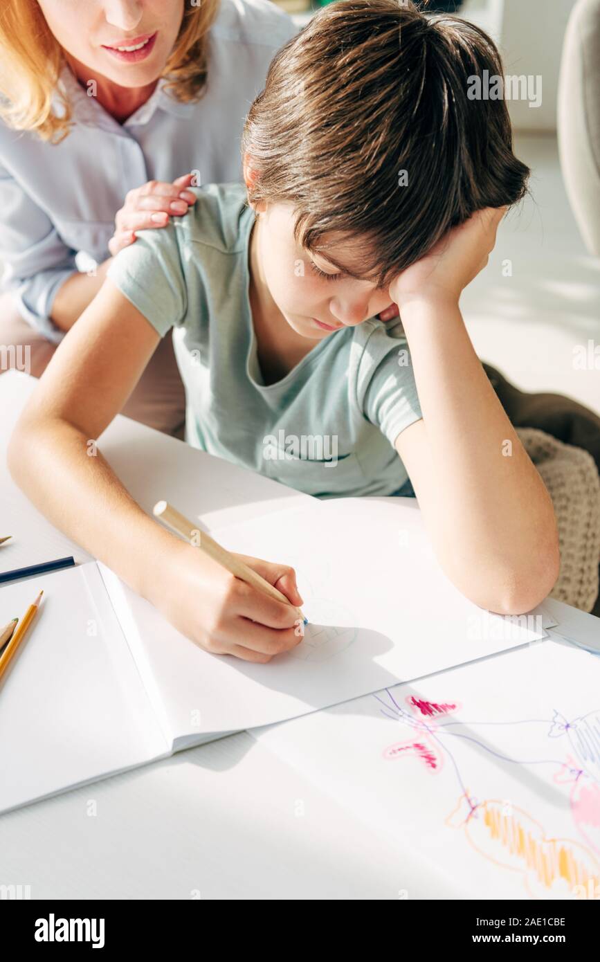 cropped view of child psychologist  and sad kid with dyslexia drawing with pencil Stock Photo