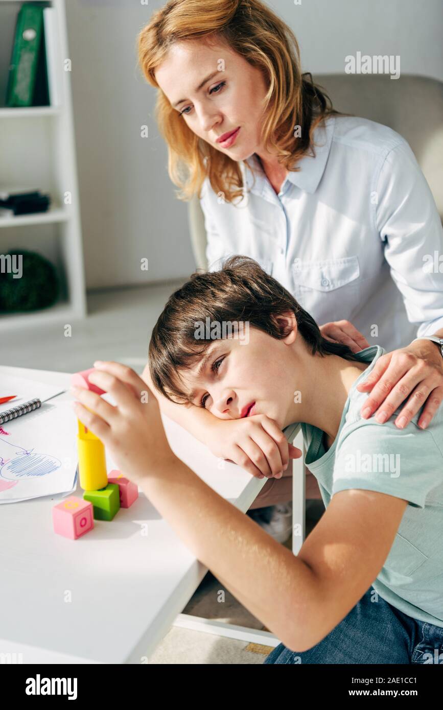 kid with dyslexia playing with building blocks and child psychologist