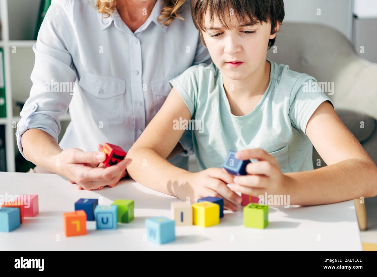 cropped view of child psychologist and kid with dyslexia playing with building blocks Stock Photo