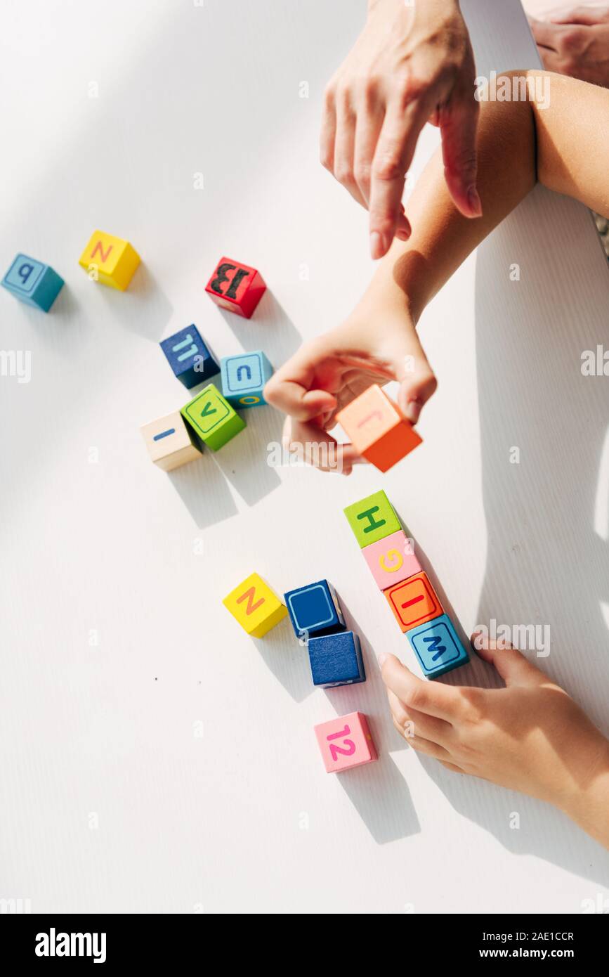 cropped view of child psychologist and kid with dyslexia playing with building blocks Stock Photo