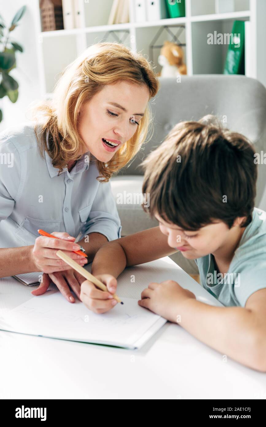 kid with dyslexia and child psychologist drawing with pencils Stock