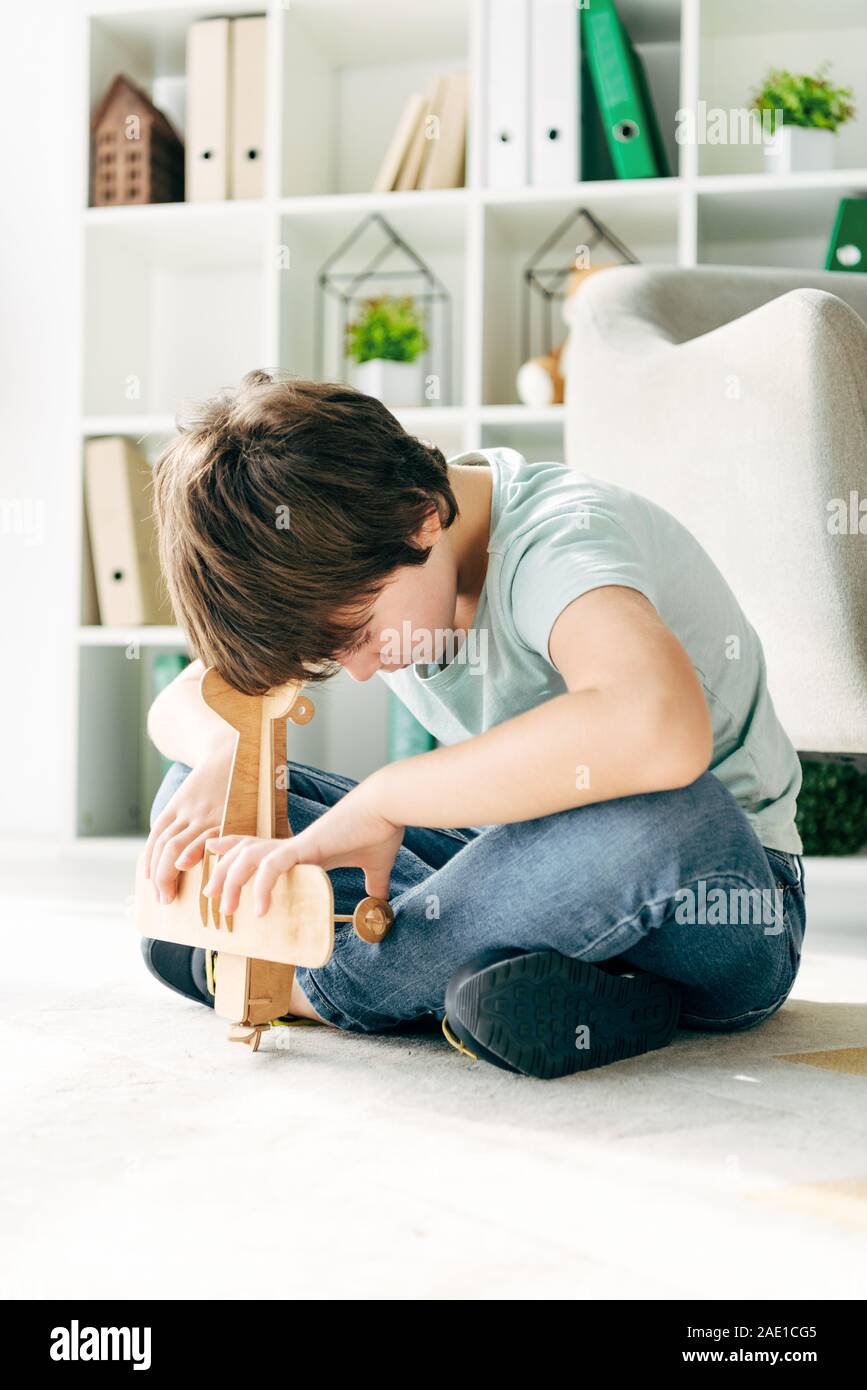 kid with dyslexia sitting on floor and holding wooden plane Stock Photo ...